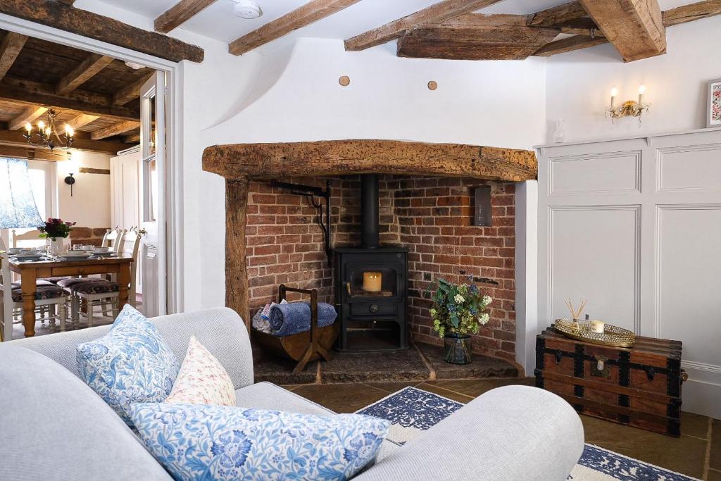 un soggiorno con camino in mattoni e divano di Joe's Cottage a Bridgnorth