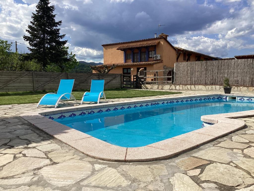 una piscina con 2 sillas azules y una casa en FINCA MAS GUIXOT relax y natura, en Montagut