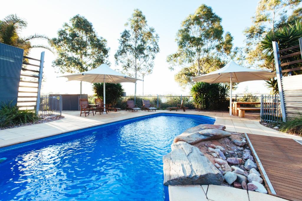 a swimming pool with two umbrellas and a pool at Majestic Oasis Apartments in Port Augusta