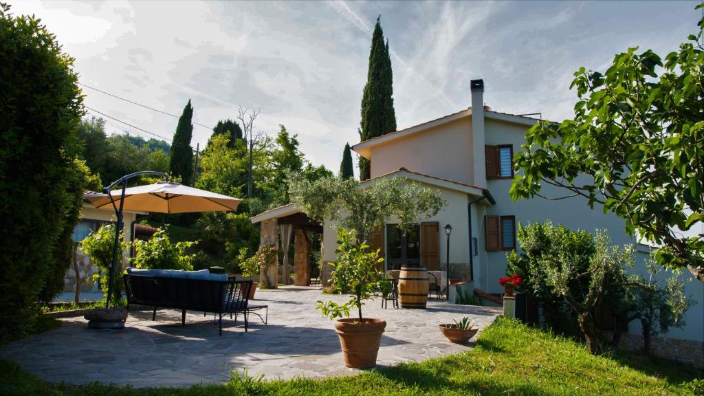 une terrasse avec un parasol en face d'une maison dans l'établissement Casa Vista della Roccia, à Volterra