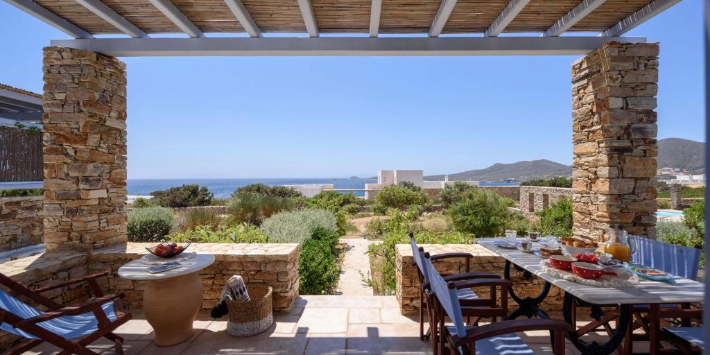 eine Terrasse mit Tischen und Stühlen und Meerblick in der Unterkunft Antiparos Luxury Villas in Andiparos