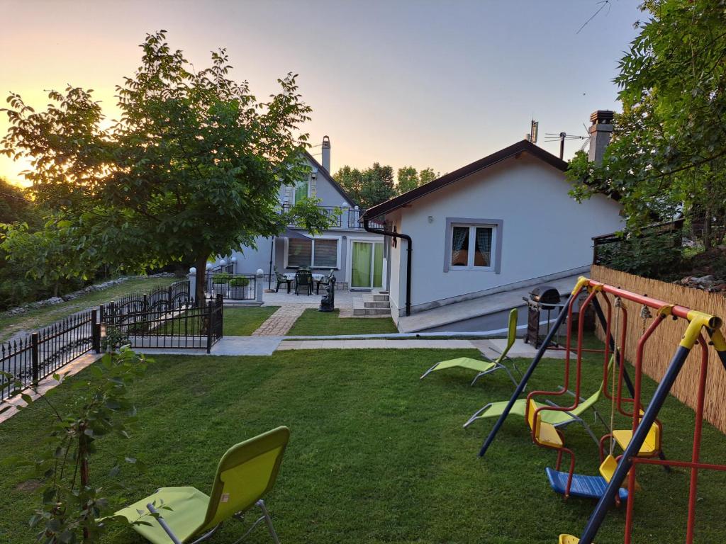 um quintal com um baloiço e uma casa em Kuća za odmor "Arija" em Zlobin