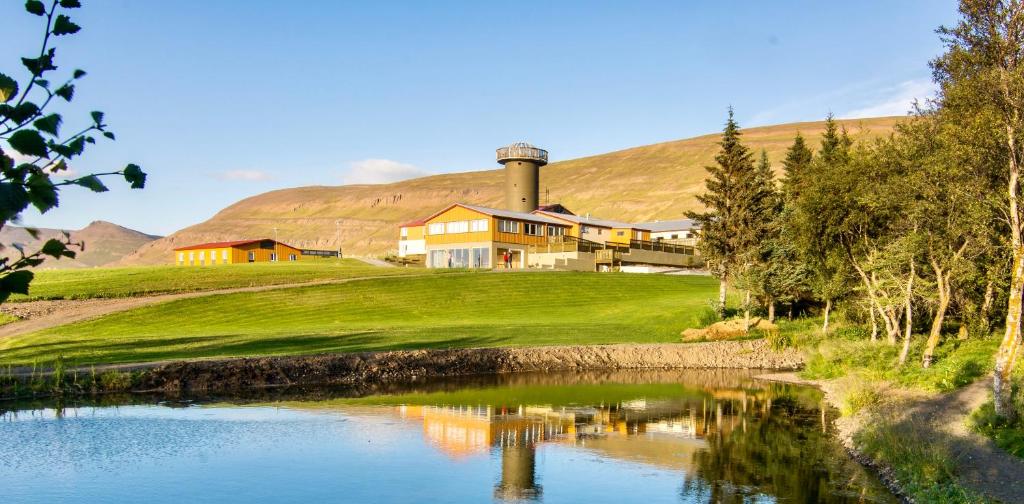 a house on a hill next to a body of water at Hotel Natur Akureyri in Akureyri