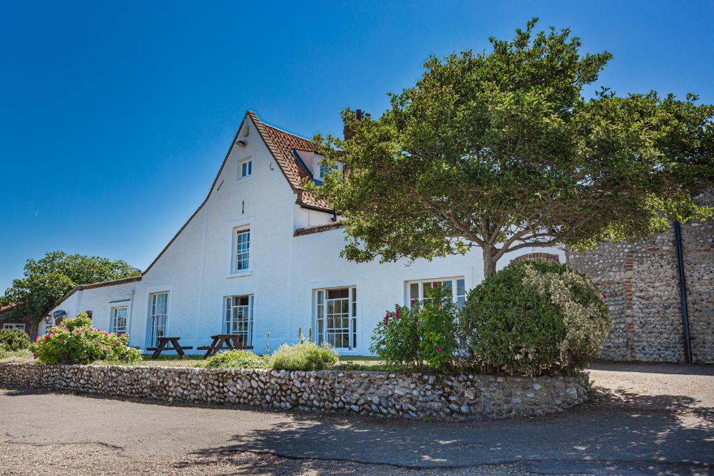 une maison blanche avec un arbre en face dans l'établissement The Manor Coastal Hotel & Inn, Blakeney, Norfolk, à Blakeney