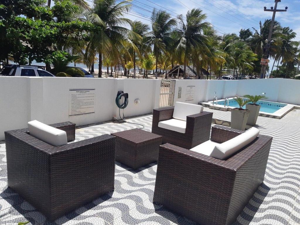 a patio with wicker furniture and a swimming pool at Flat Beira-Mar Maragogi in Maragogi