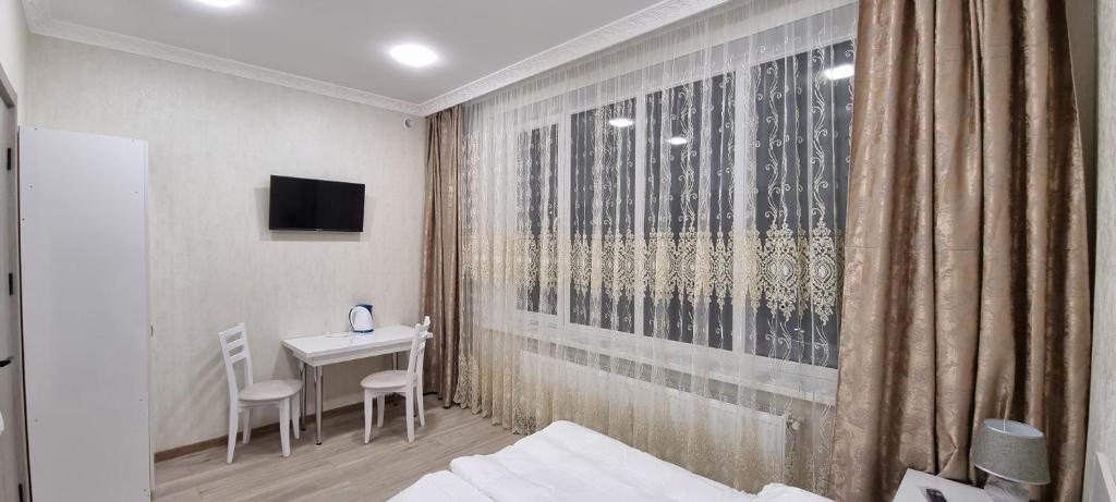 una stanza con un letto, un tavolo e una scrivania di Sonya a Ninotsminda