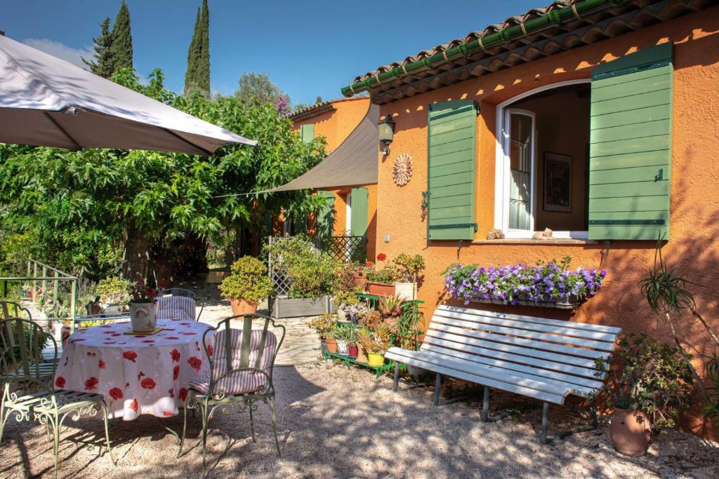 a table and a bench in front of a house at Le Clos des Oliviers in Le Rouret