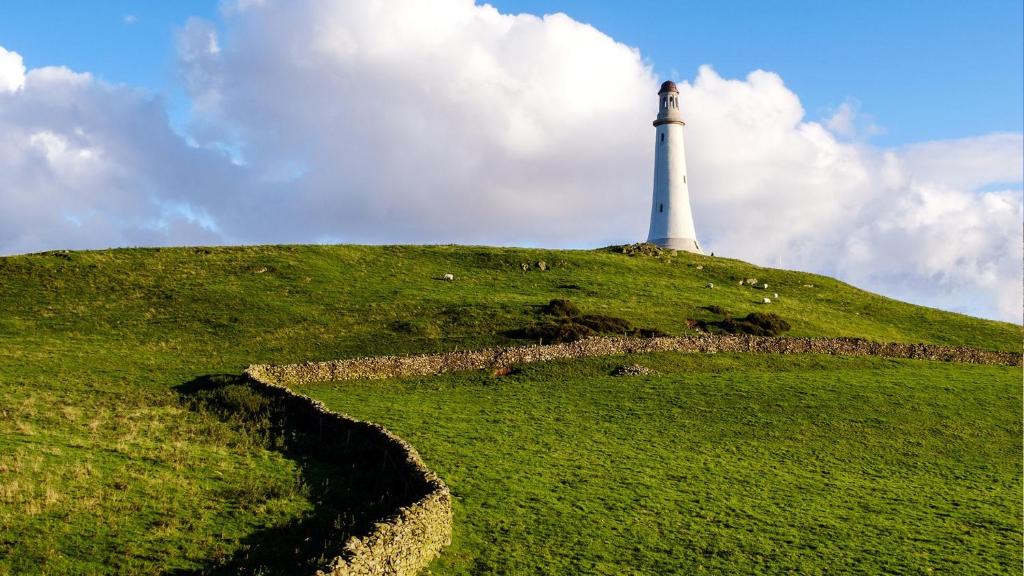 a lighthouse on top of a green hill at Burlington Cottage - Ulverston, Lake District. in Ulverston