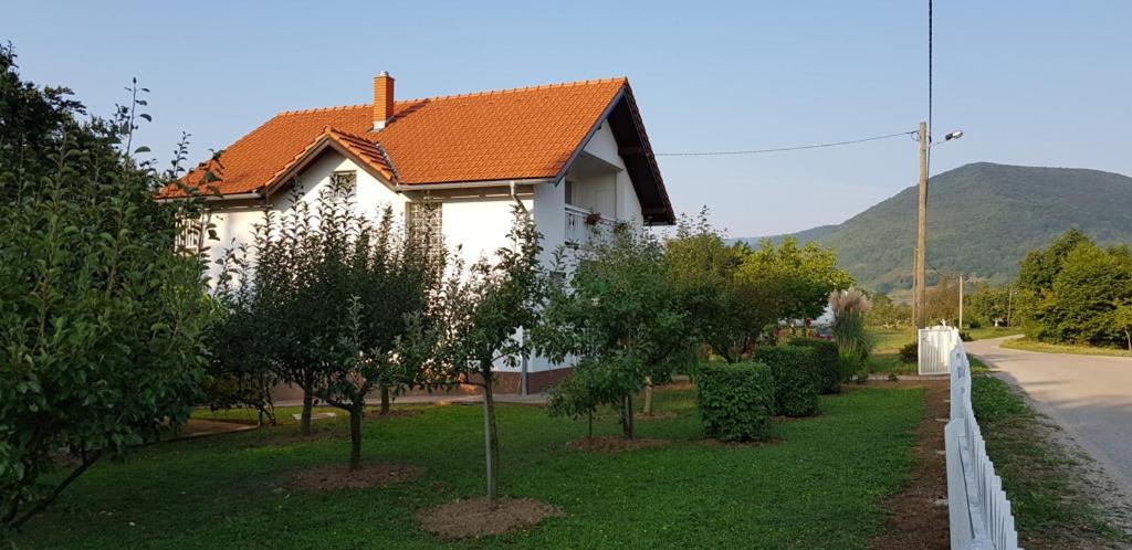 uma casa com um telhado laranja e algumas árvores em PLITVICE OAZA MIRA em Smoljanac
