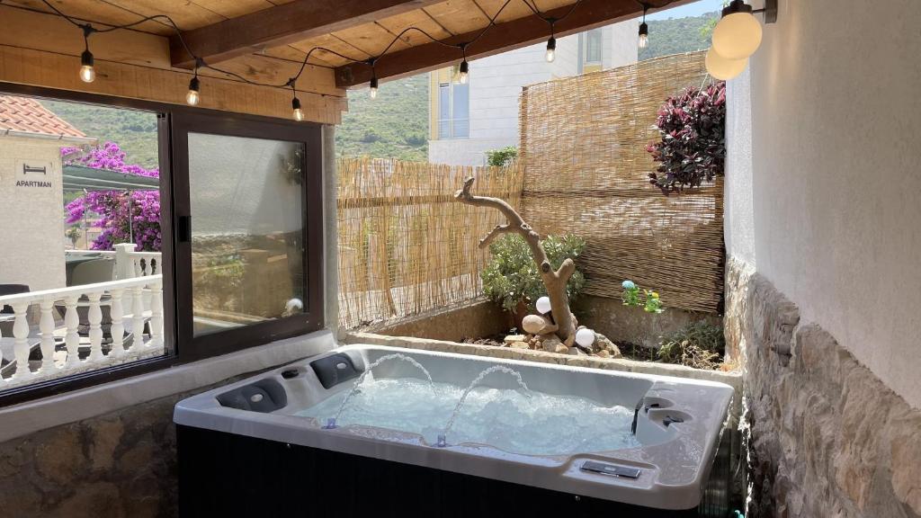 bañera de hidromasaje en una habitación con ventana en ViSun Apartment 3, en Vis