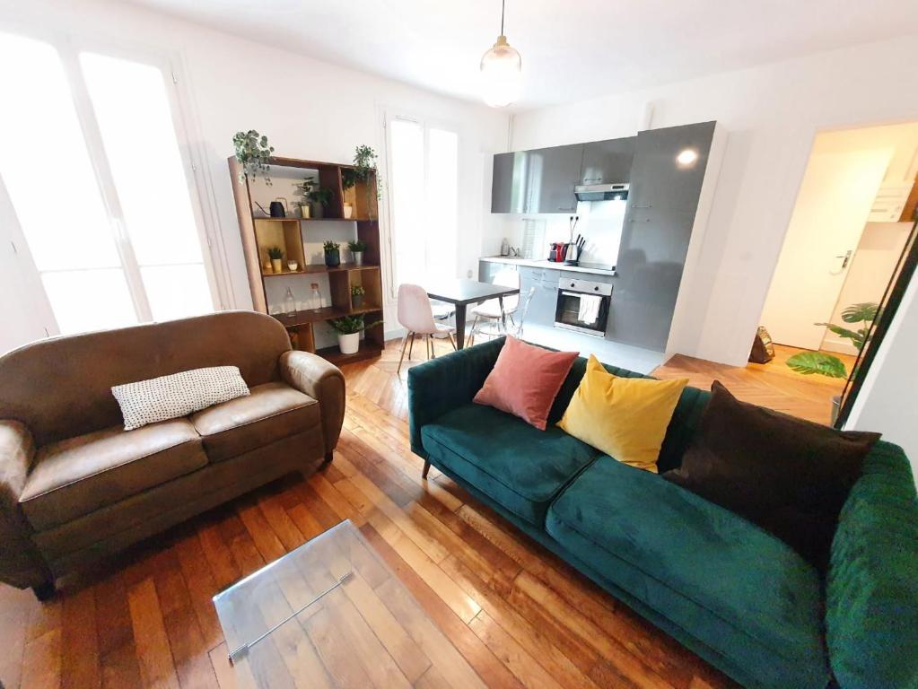 a living room with a green couch and a kitchen at Home Sweet Home Ordener Marcadet in Paris