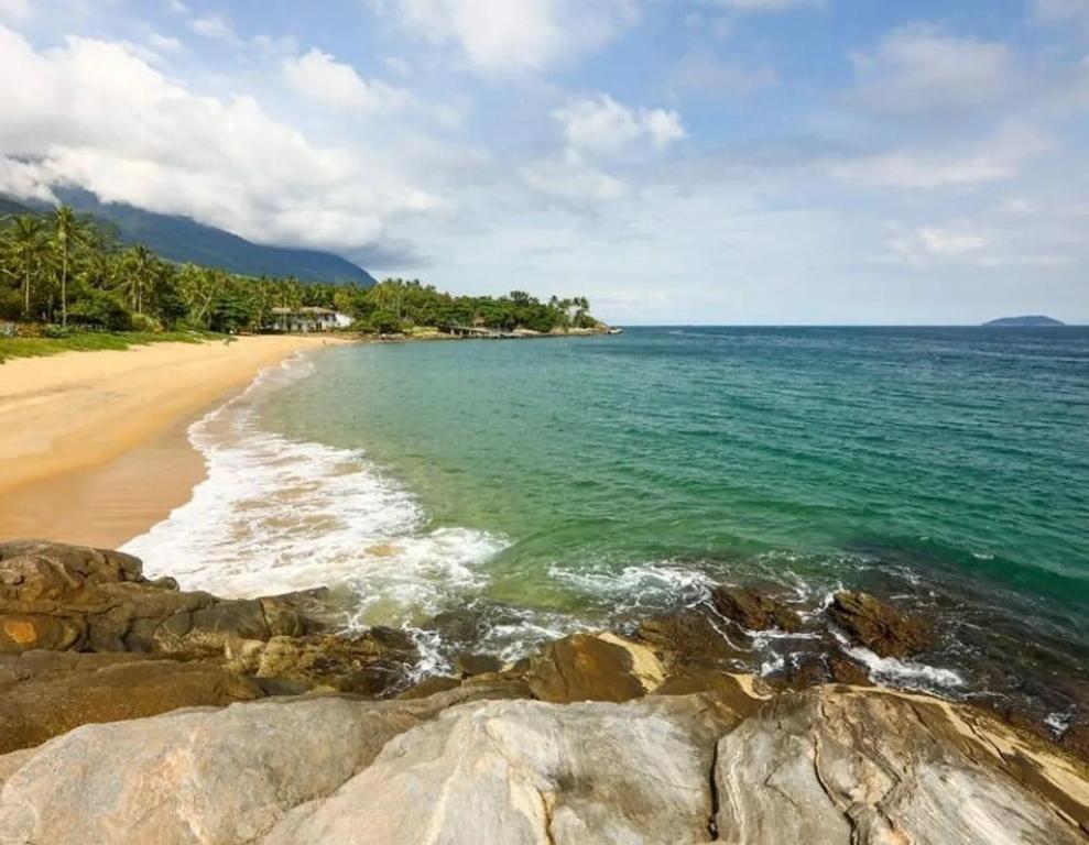 een uitzicht op een strand met rotsen en de oceaan bij Chalés Ilhabela Esmeralda in Ilhabela