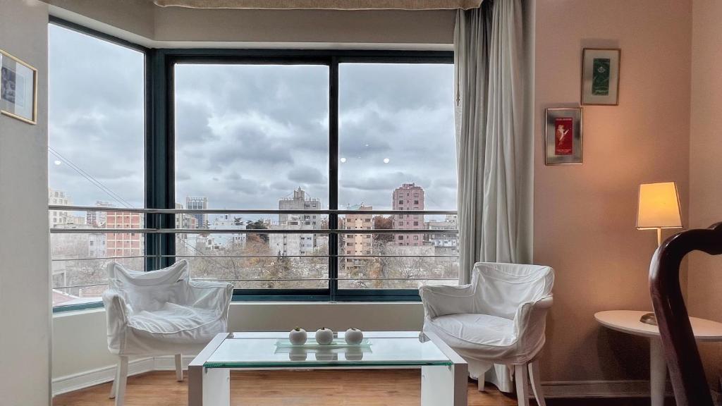 een kamer met een groot raam met witte stoelen en een tafel bij Amplio, moderno e impecable departamento en la mejor ubicacion de Mendoza in Mendoza