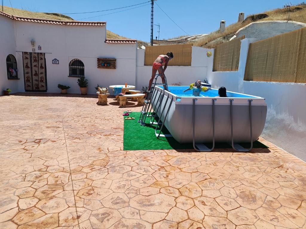 Ein Mann steht neben einem Pool im Garten. in der Unterkunft Cueva la kililla in Guadix