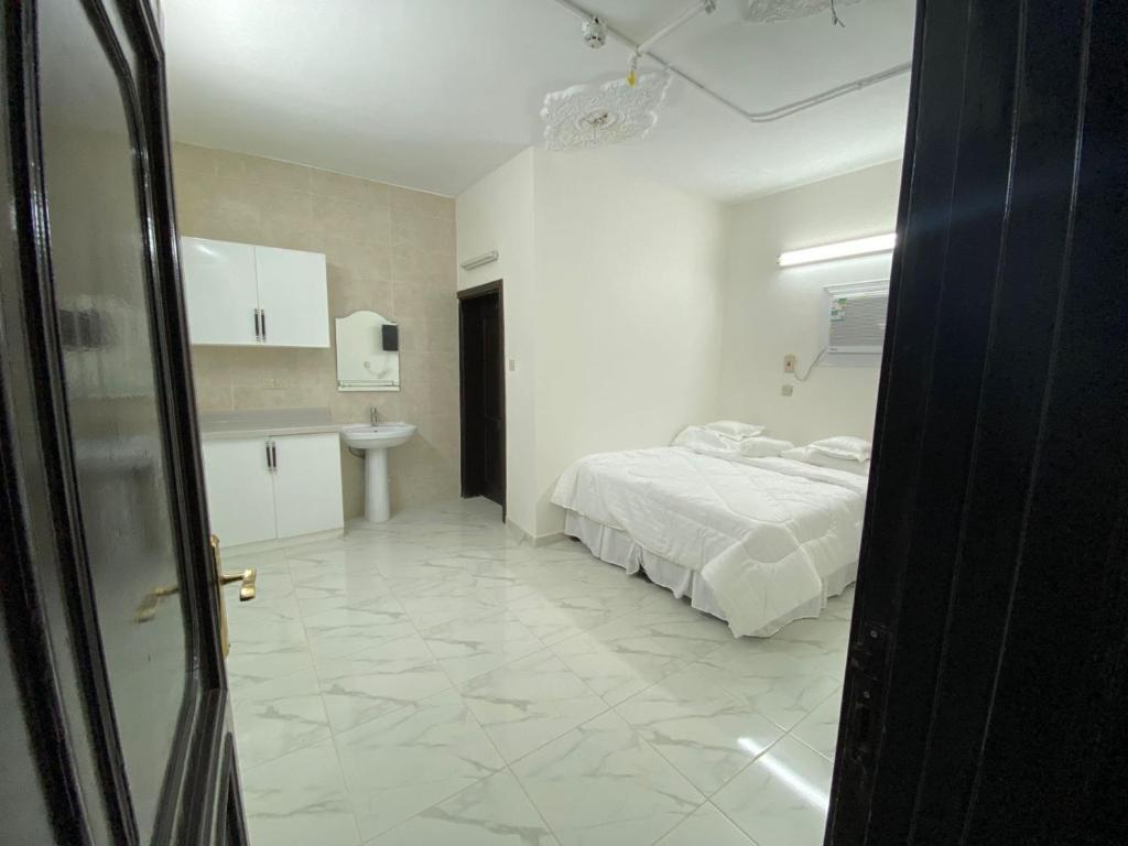 a white bedroom with a bed and a sink at شذا البستان in Al Madinah