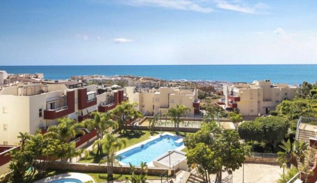 - une vue sur un complexe avec une piscine et l'océan dans l'établissement Ático duplex en Benalmádena vistas al mar y montaña dos habitaciones, à Benalmádena