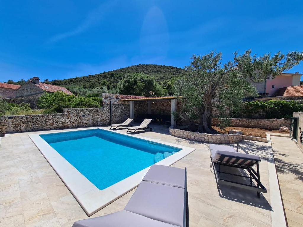 uma piscina com cadeiras e uma villa em Olive Tree - House with Pool em Vinišće