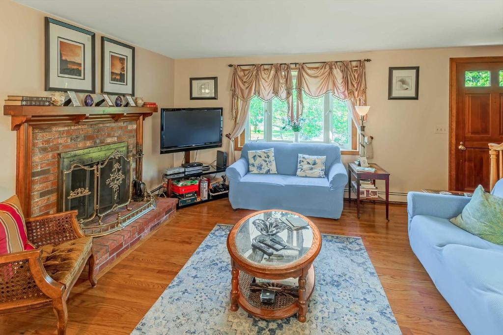a living room with a blue couch and a fireplace at Pet-Friendly West Yarmouth Home, Half Mi to Beach! in West Yarmouth