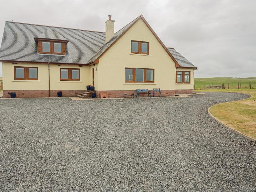 a house with a gravel driveway in front of it at Corsewall Castle Farm Lodges in Kirkcolm