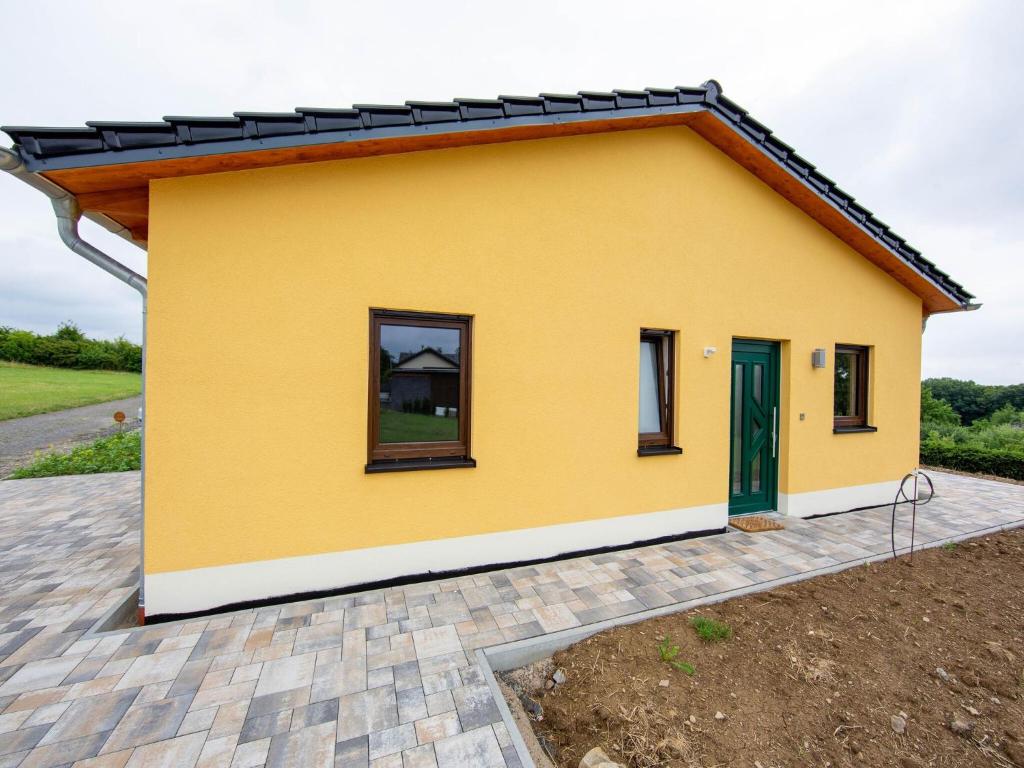 a small yellow house with a green door at Ferienhaus Eifelruhe in Filz in Filz