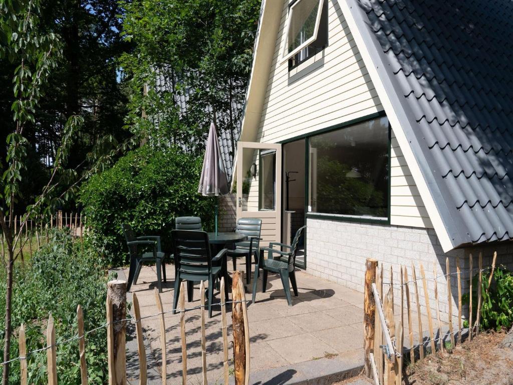 een patio met een tafel en stoelen en een parasol bij Cosy holiday home in Eerbeek with balcony terrace in Eerbeek