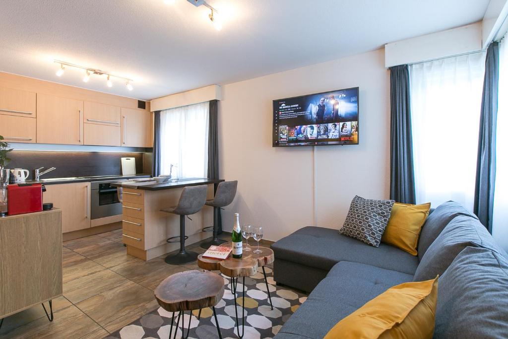 a living room with a blue couch and a kitchen at Spirit Apartments - Studio 2 - Küche - Parkplatz in Engelberg