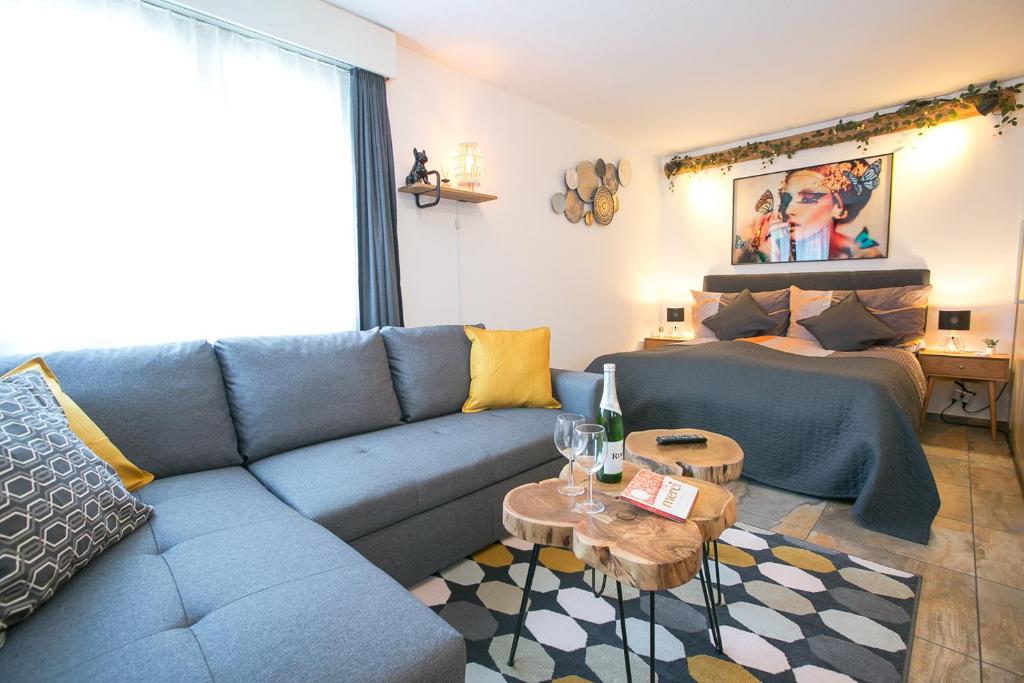 sala de estar con sofá azul y cama en Spirit Apartments - Studio 1 und 2 - Küche - Parkplatz en Engelberg