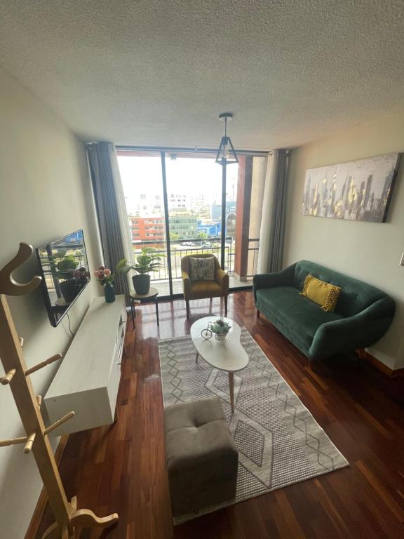 Una sala de estar con un sofá verde y una mesa. en Departamento completo en Miraflores Surquillo, en Lima