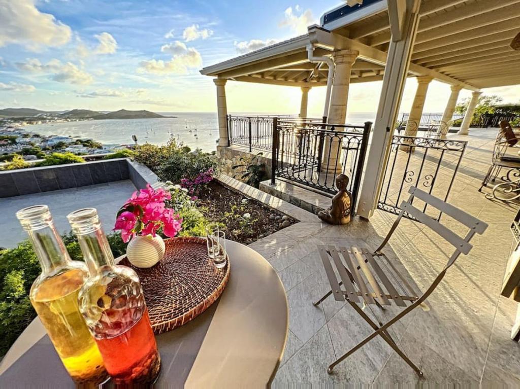 een tafel met twee flessen alcohol op een patio bij Blue Room in a shared Villa Diamant with communal pool and sea view in Grand Case