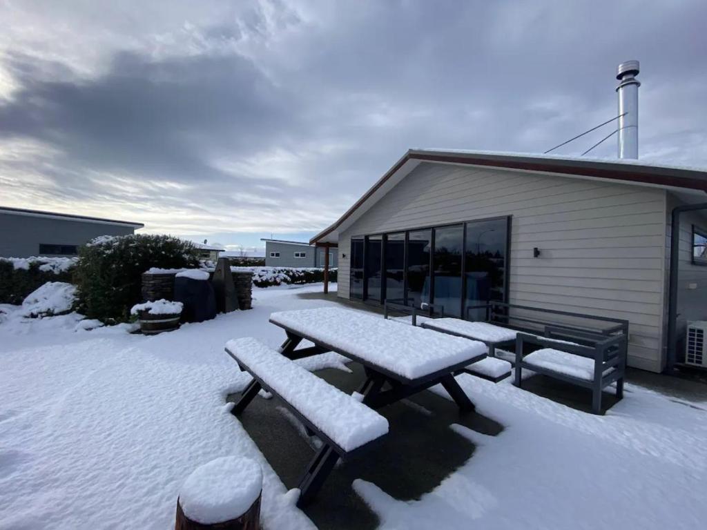 a picnic table covered in snow next to a building at Hidden Gem, Ideal on Irishman FREE WIFI in Twizel