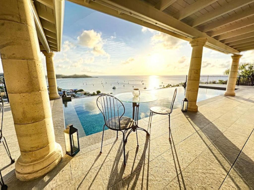 a table and chairs on a patio with a view of the water at Studio Aloe in shared Villa Diamant, infinity pool, sea view in Grand Case