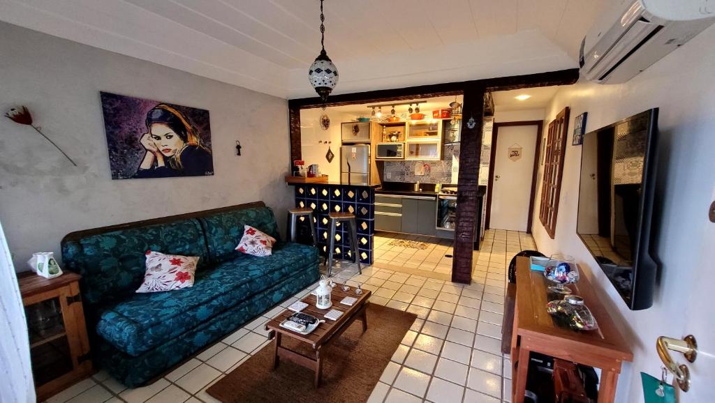 ein Wohnzimmer mit einer grünen Couch und einer Küche in der Unterkunft Maison Bardot 1 - Casa em condomínio para 4 em Geribá, Búzios in Búzios