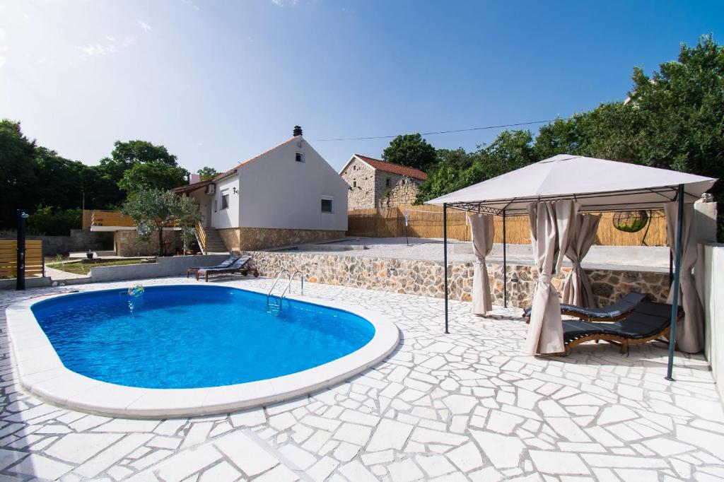 uma piscina com um guarda-sol e um pátio em House Manda Adriatic em Skradin