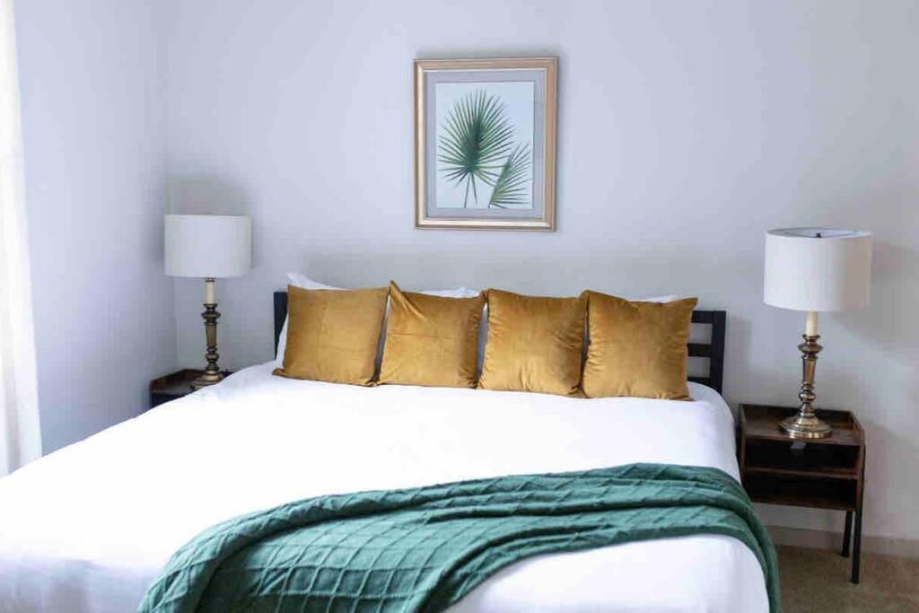 um quarto com uma grande cama branca com almofadas douradas em AMPLIFY SPACES 1 and 2 BR Apartments, Downtown Birmingham, UAB em Birmingham