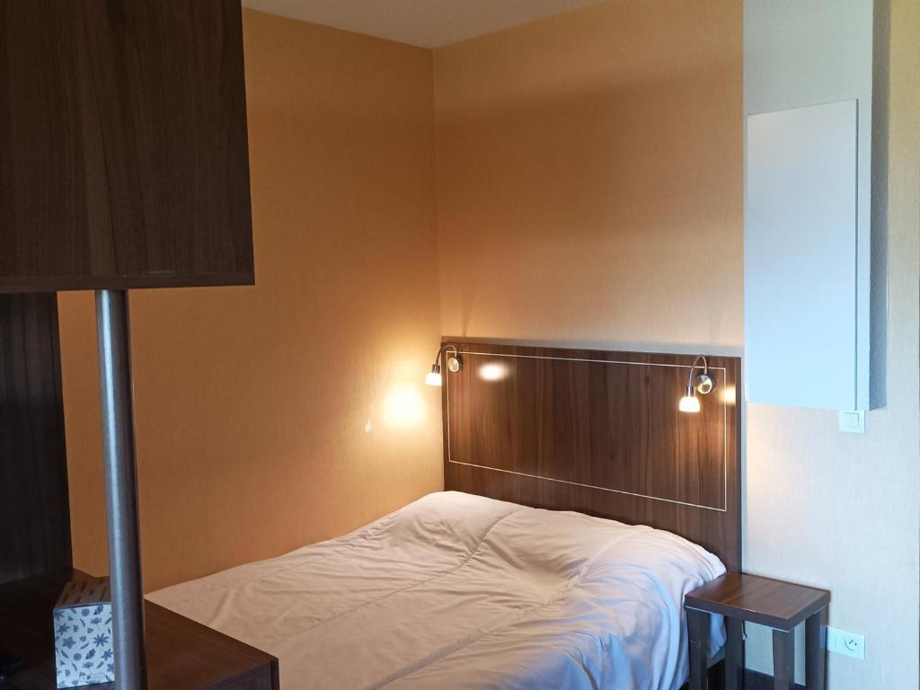 - une chambre avec un lit doté d'une tête de lit en bois et de lumières dans l'établissement Studio à Jausiers avec terrasse, piscine chauffée et parking, proche du Mercantour - FR-1-165B-43, à Jausiers