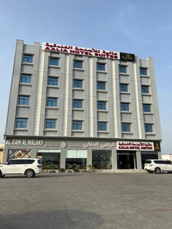 Aalia Hotel Suites في صحار: مبنى كبير فيه سيارات تقف امامه