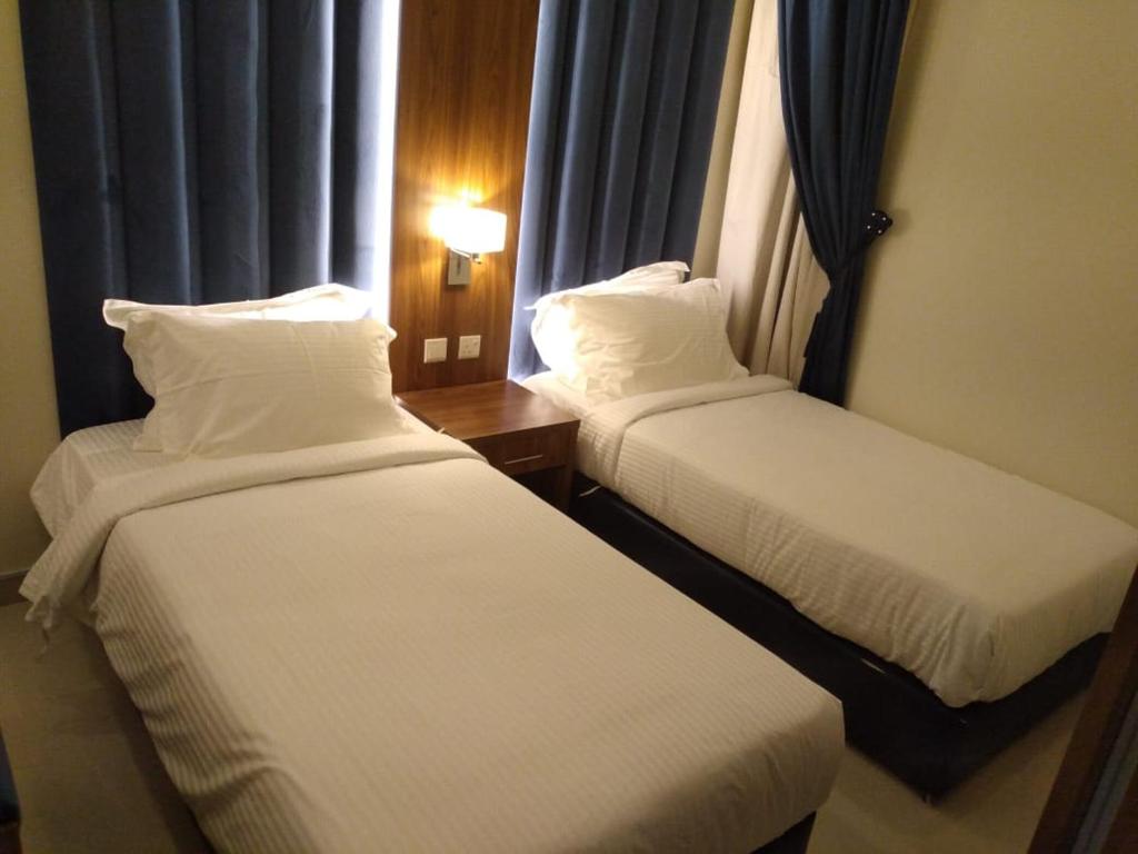 a hotel room with two beds and a window at Reef Al Qassim Hotel Apartments in Buraydah