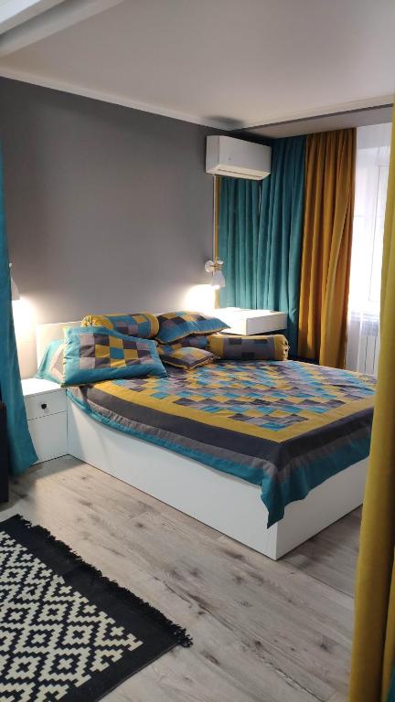 a bedroom with a large bed with blue curtains at Apartment on Panfilova 114 in Almaty