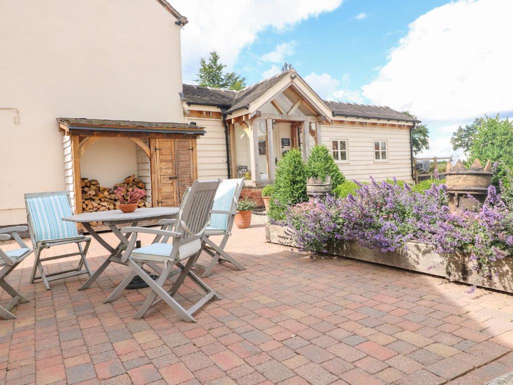 un patio con tavolo, sedie e una casa di Bellamour End Cottage a Rugeley