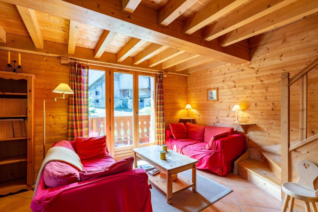 ein Wohnzimmer mit zwei roten Sofas und einem Tisch in der Unterkunft Quiet apartment near the slopes in La Clusaz