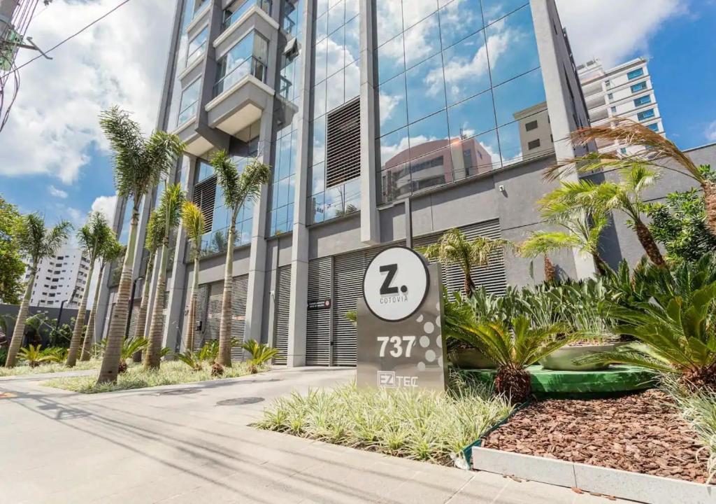 a sign in front of a building with palm trees at Studios Sampa - Moema Cotovia in Sao Paulo