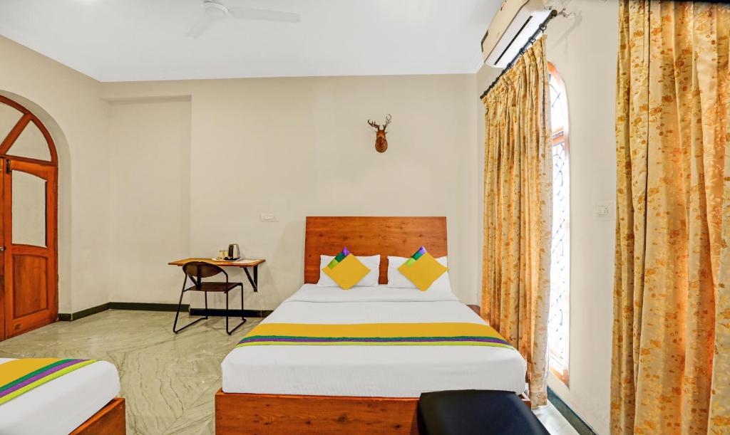 a bedroom with a bed and a desk and a window at Itsy By Treebo - Anurag Inn in Mysore