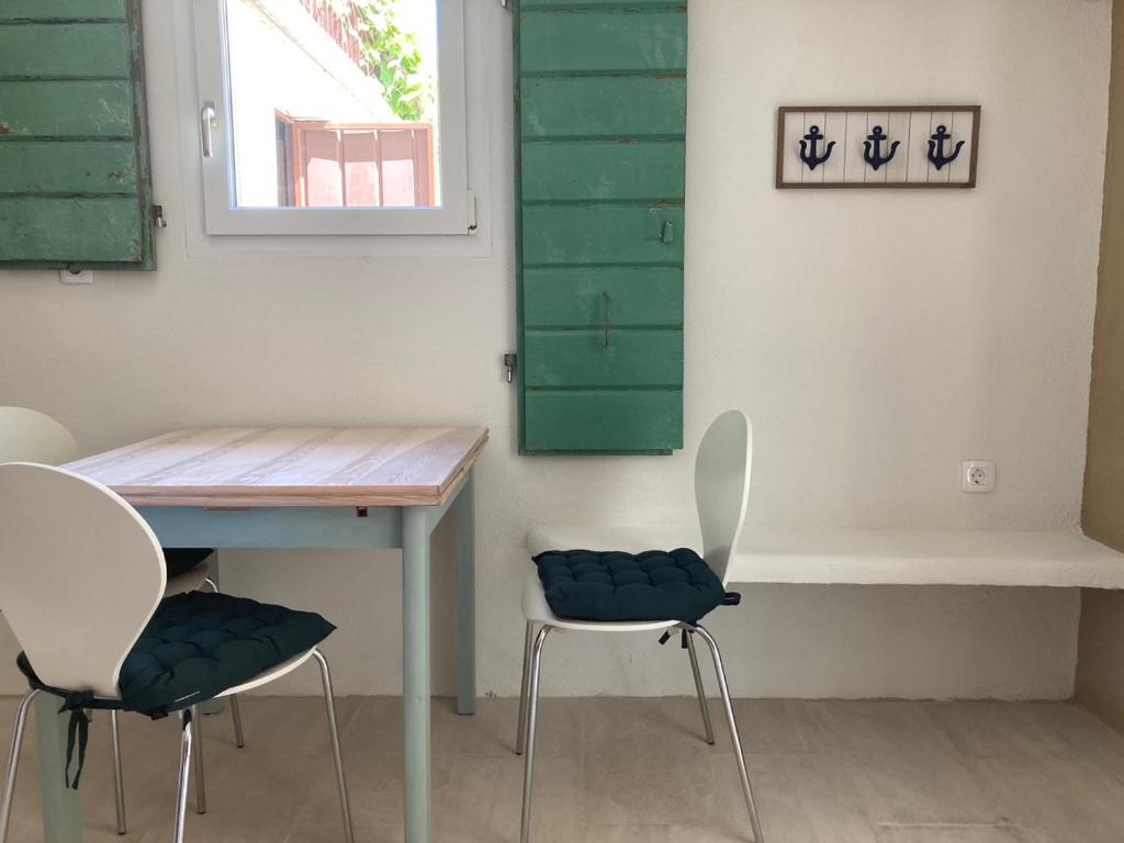 einen Tisch und Stühle in einem Zimmer mit grünem Rollladen in der Unterkunft Apartments Mimoza Komiza in Komiža