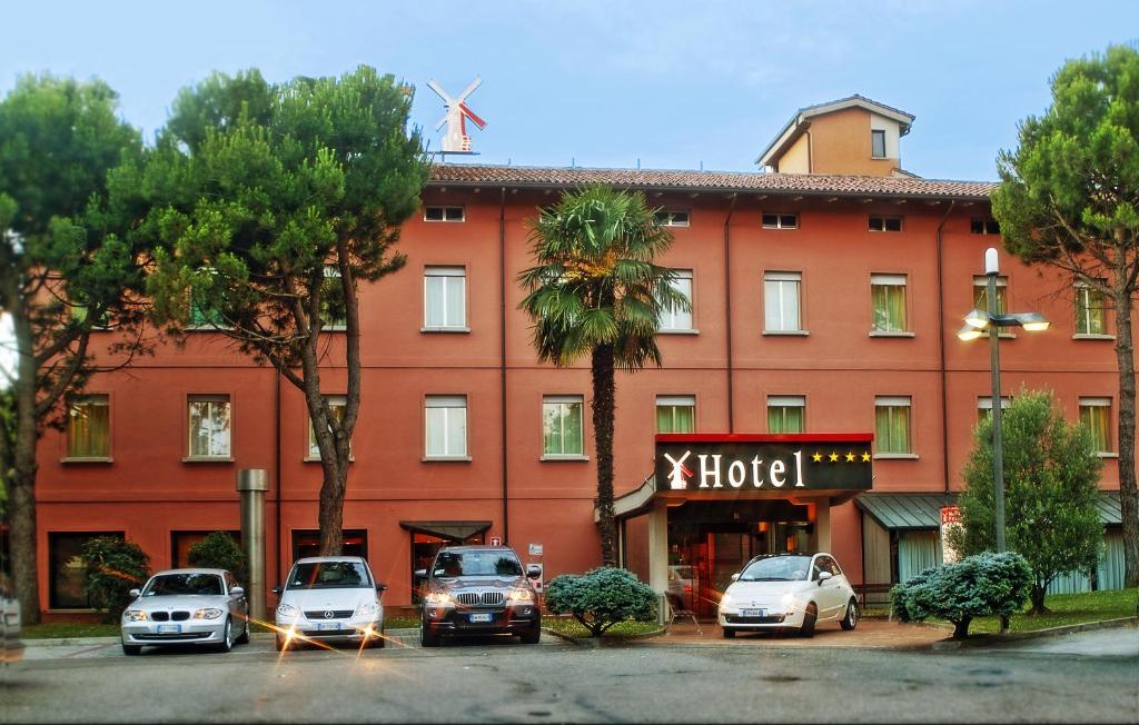 un grand bâtiment rouge avec des voitures garées devant lui dans l'établissement Hotel Molino Rosso, à Imola