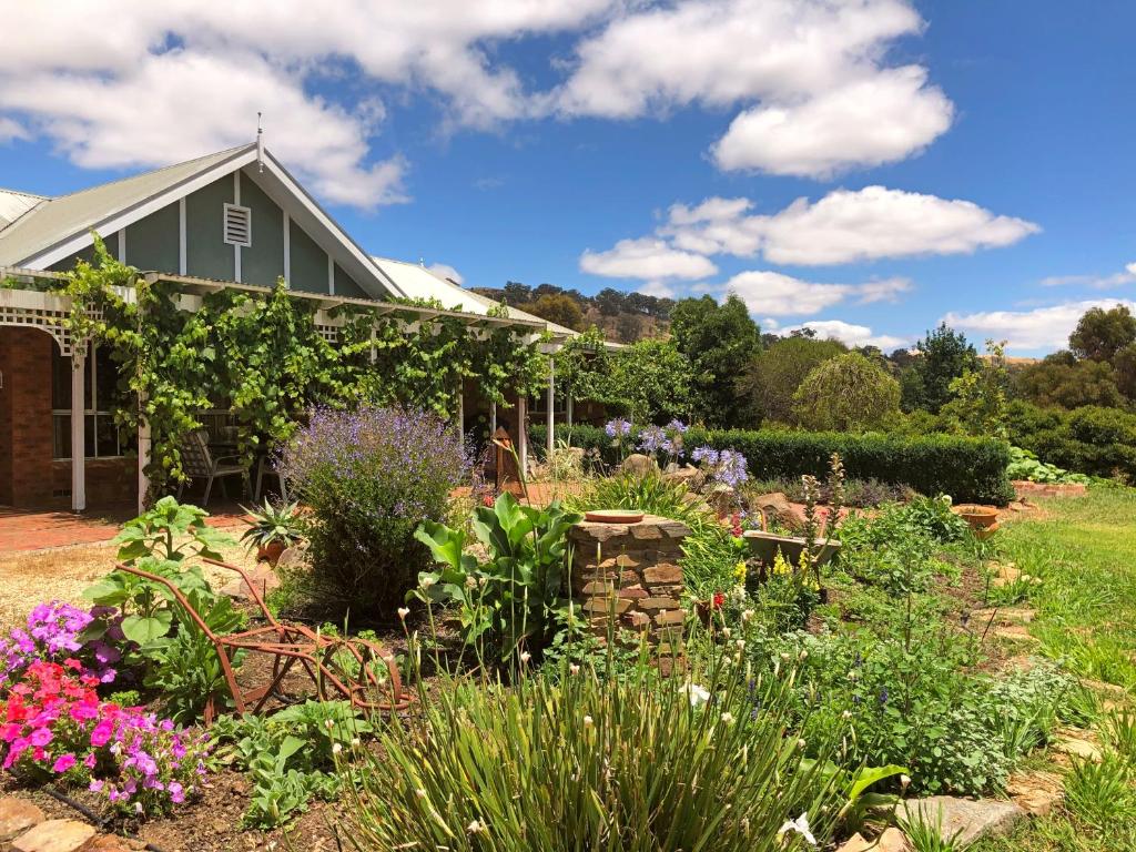 a garden in front of a house with flowers at Belkampar Retreat - Authentic Farm Style Home - Perfect For Families and Large Groups! in Bonnie Doon