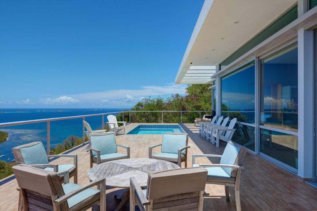 a balcony with a table and chairs and a swimming pool at Happy Days Villa C in Fajardo