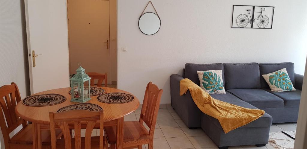 un salon avec une table et un canapé bleu dans l'établissement T2 Apt Berck avec parking, 1.8km plage, à Berck-sur-Mer
