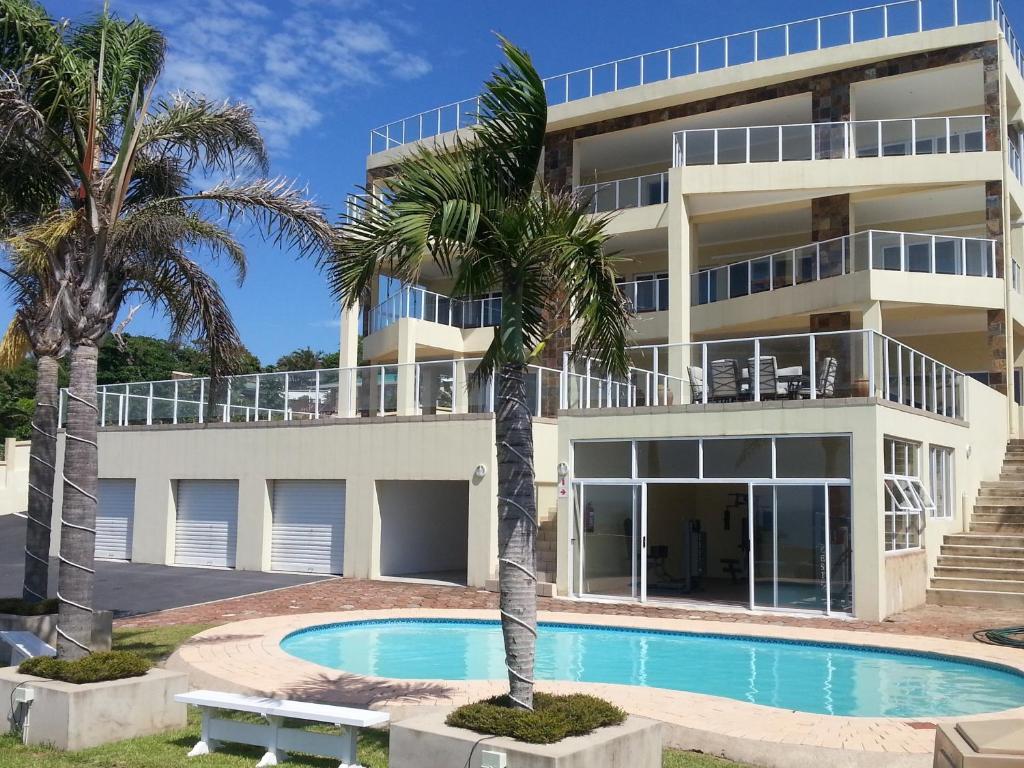 an apartment building with a swimming pool and palm trees at The Homestead Margate - South Africa in Margate