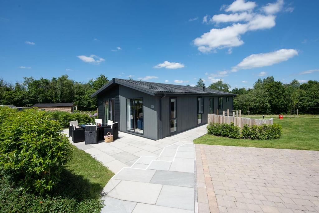 ein schwarzes Haus in einem Garten in der Unterkunft Buttercup Lodge, 33 Roadford Lake Lodges in Lifton