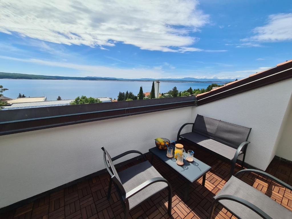 een balkon met een tafel en stoelen en uitzicht op het water bij Romantic New Superior apartments close to Sandy and pebble beach in Crikvenica